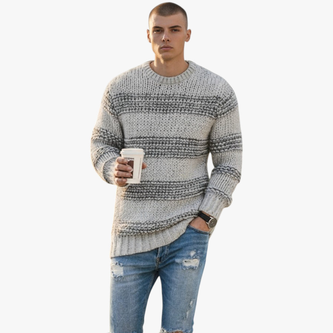 Man wearing a patterned sweater and jeans holding a coffee cup on a white background