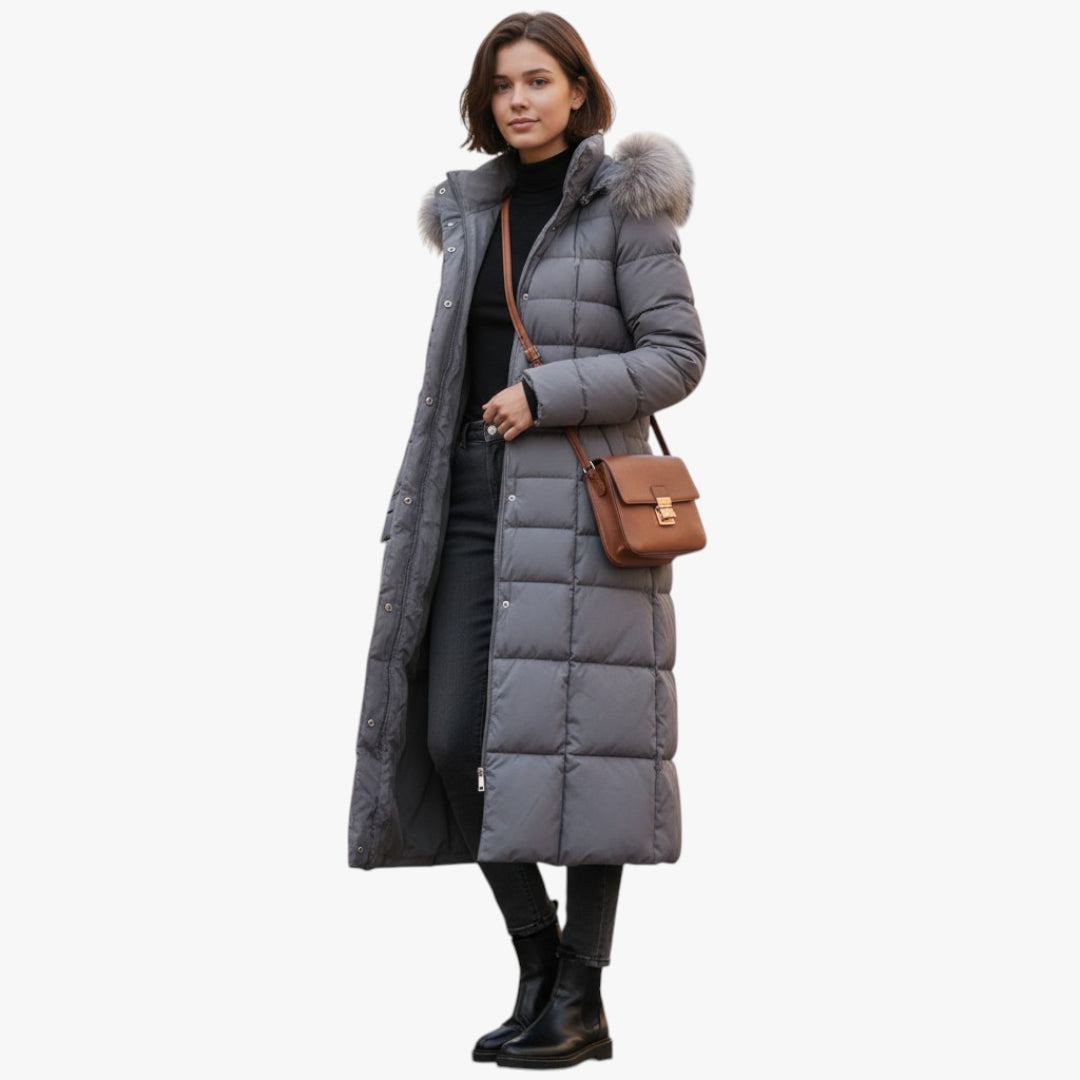 Woman wearing a long gray puffer coat with a fur hood on a white background