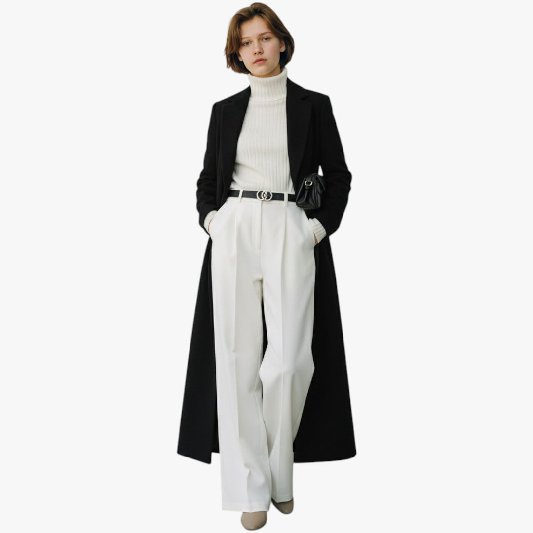 Person wearing a black coat over a white outfit on a white background