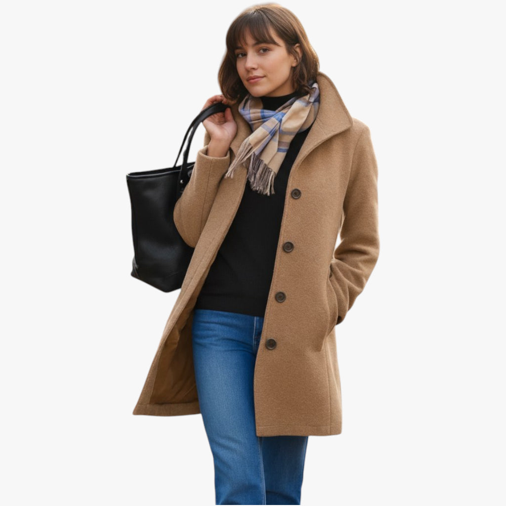 Woman wearing a brown coat, black sweater, blue jeans, and a black tote bag on a white background