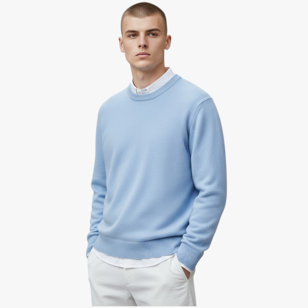 Man wearing a light blue sweater over a white shirt on a white background