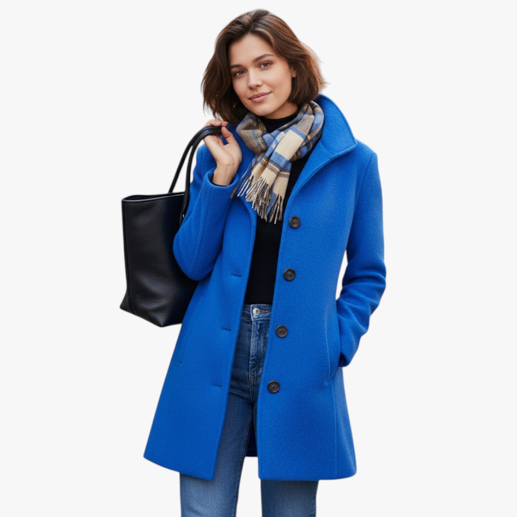 Woman wearing a blue coat with a black bag and plaid scarf on a white background