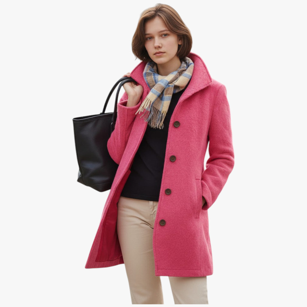 Woman wearing a pink coat with a black bag and plaid scarf on a white background